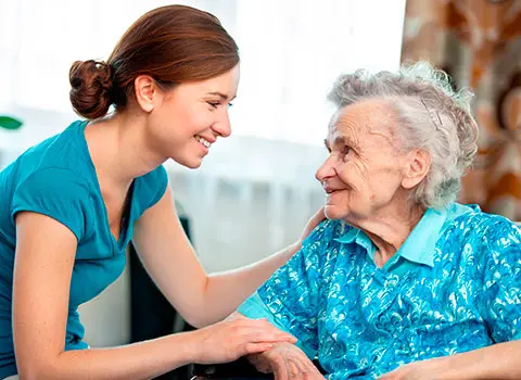 AdobeStock_44407430 - Blue Water Homecare Young female caregiver smiles at an elderly female woman
